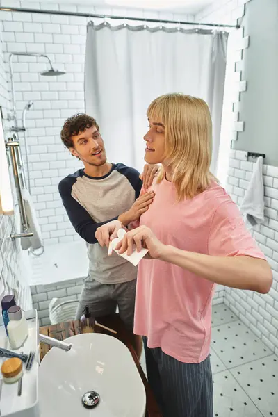 Two men share a playful morning moment in a bright bathroom while getting ready together. — Stock Photo