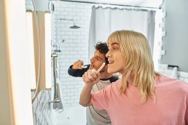 Two men enjoy a fun morning routine while brushing their teeth in a stylish bathroom. — Stock Photo