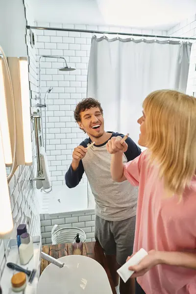 Couple aimant se brosse les dents ensemble, profitant d'un rituel matinal gai dans une salle de bain confortable. — Photo de stock