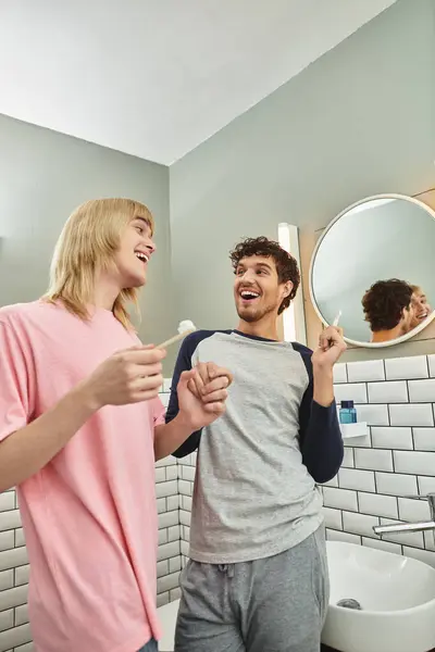 Two men share laughter and intimacy while brushing their teeth in a bright bathroom. — Stock Photo