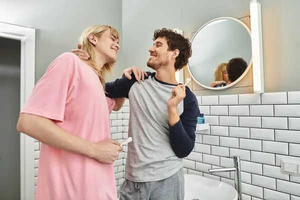 Two men share playful smiles while getting ready in their warm and inviting bathroom. — Stock Photo