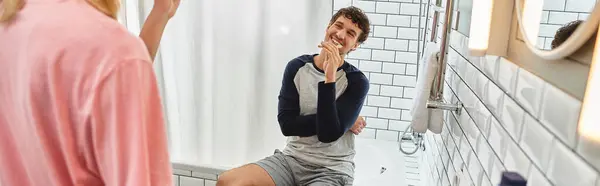 A joyful gay couple shares a lighthearted interaction while getting ready in their stylish bathroom. — Stock Photo