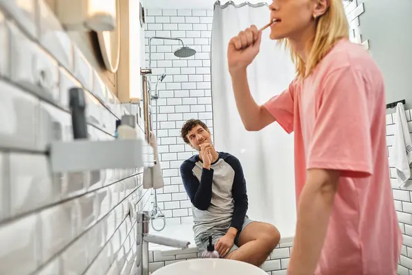 Two men share a warm moment as they brush their teeth and connect in a bright bathroom. — Stock Photo