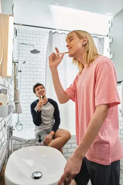 Two men express their love while brushing their teeth in a bright, cozy bathroom together — Stock Photo