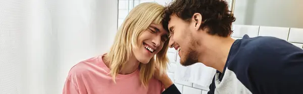 Two joyful men share a tender moment, smiling at each other in a warm and inviting space. — Stock Photo