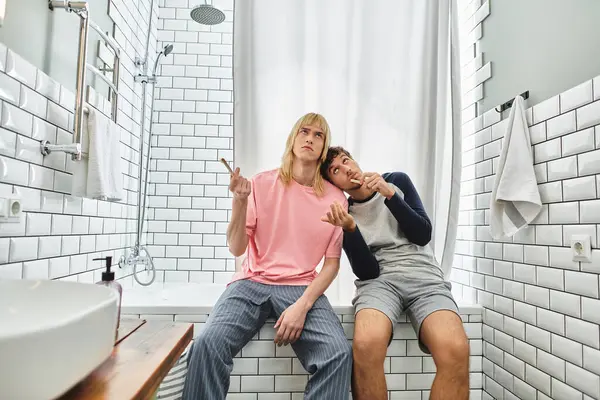 Two men share laughter and joy while relaxing in a warmly lit bathroom space together. — Stock Photo