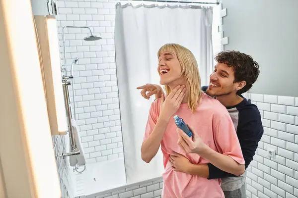 Two men are playfully enjoying a loving moment in their bathroom, sharing smiles and laughter. — Stock Photo