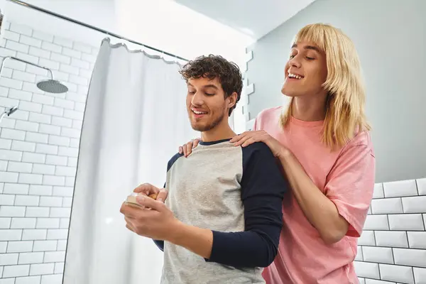 Two men enjoy a lighthearted moment together in their cozy bathroom, sharing smiles and laughter. — Stock Photo