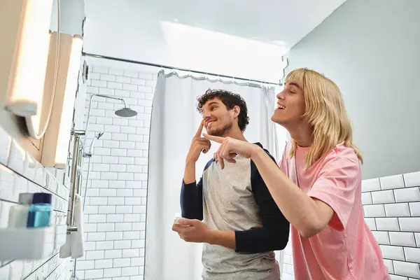 Couple partage des rires et des moments intimes tout en se préparant dans un espace de salle de bain lumineux. — Photo de stock