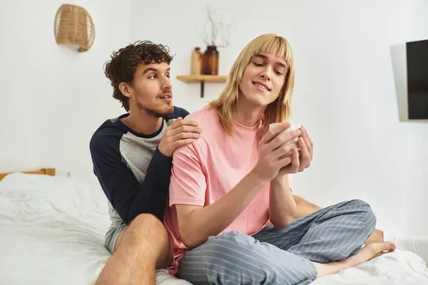 Two men enjoy each others company while relaxing on a bed in a warm and inviting space. — Stock Photo