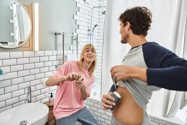 Zwei Männer lachen, während sie sich in ihrem gemütlichen Badezimmer spielerisch eincremen. — Stockfoto