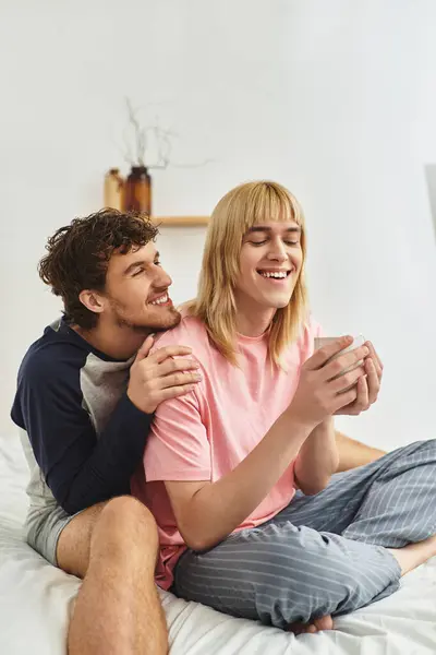Deux hommes profitent d'un doux moment ensemble assis sur un lit, respirant l'amour et le bonheur. — Photo de stock