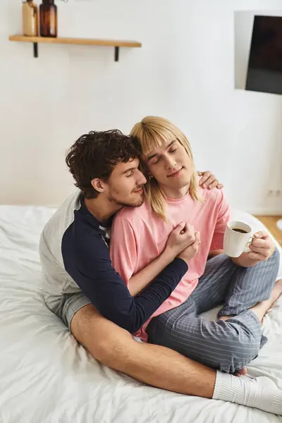 A tender moment between two men in a peaceful setting, sharing love and coffee in bed. — Stock Photo