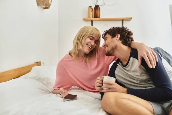 Two men share a warm smile in bed with drinks, highlighting their love and bond. — Stock Photo