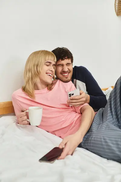 Due uomini si coccolano su un letto, condividono sorrisi e risate mentre si godono reciprocamente compagnia. — Foto stock