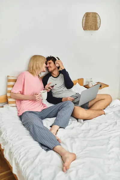 Two men share a sweet moment on their bed, sipping coffee and enjoying each others company. — Stock Photo
