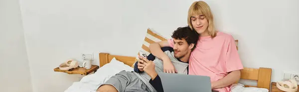 Two men relax on a bed, sharing joyous moments while engaged with a laptop. — Stock Photo