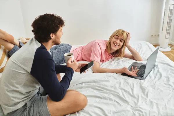 Deux hommes profitent de leur compagnie sur un lit, partageant des sourires tout en utilisant un ordinateur portable. — Photo de stock