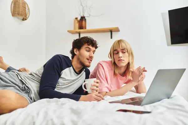 Two men share a relaxed evening together, smiling and interacting while using a laptop comfortably. — Stock Photo