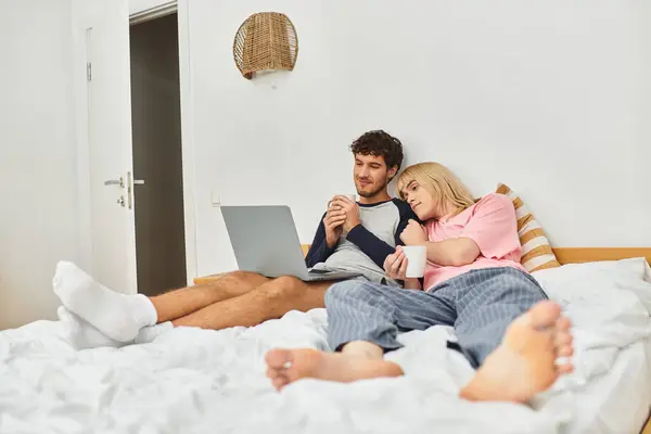 Two men relax on a bed, enjoying each others company while sipping warm beverages together. — Stock Photo