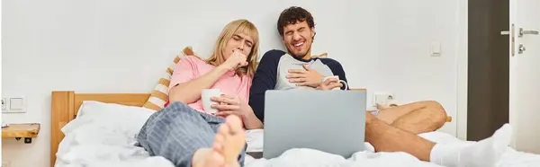 Deux hommes se blottissent sur un lit confortable tout en profitant d'une soirée cinéma amusante avec des collations et des rires. — Photo de stock