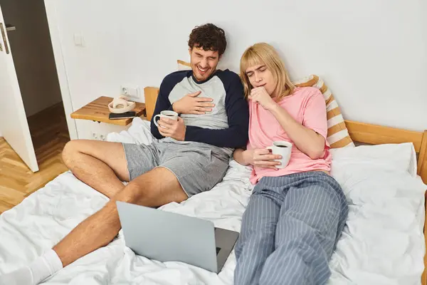 Deux hommes se détendent et s'amusent ensemble sur un lit confortable, partageant rires et chaleur. — Photo de stock