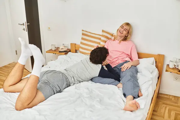 Two men cuddle affectionately on a bed, filled with laughter and warmth amid a relaxed atmosphere. — Stock Photo