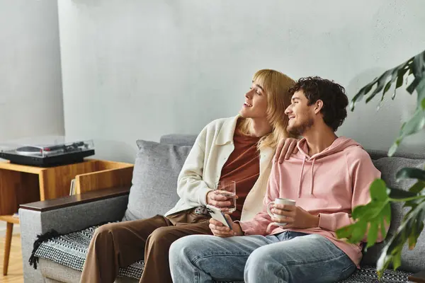 Two men share a heartfelt moment in a comfortable living room, enjoying drinks and laughter. — Stock Photo