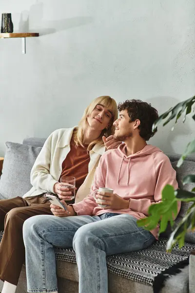 Two men sit together on a couch, sharing drinks and smiles in a warm, inviting space. — Stock Photo