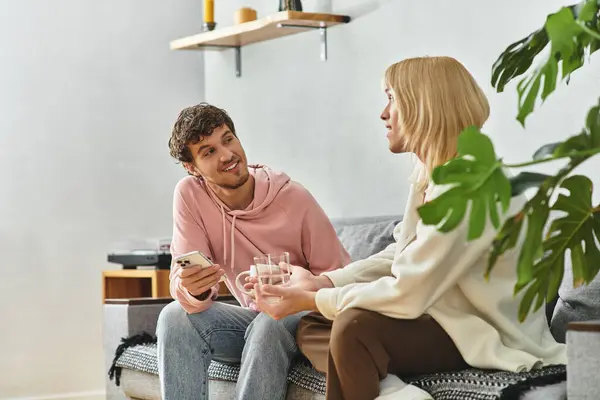 Dos hombres se sientan juntos en una cálida sala de estar, compartiendo bebidas y risas, disfrutando de su tiempo. - foto de stock