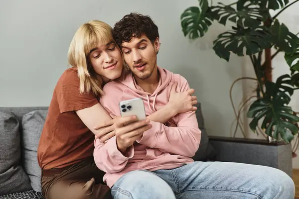 Two men share a warm embrace while looking at their smartphone, radiating love and connection. — Stock Photo