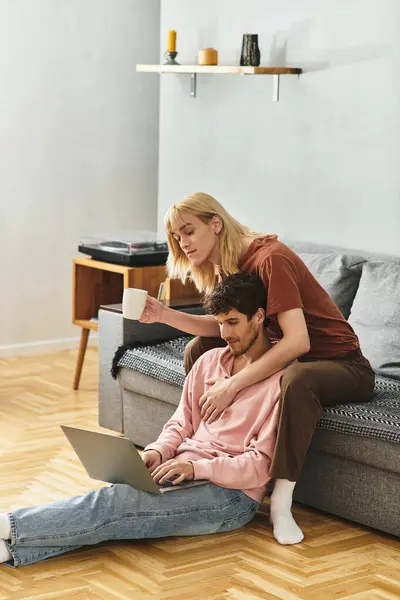 Two men enjoy coffee and work on a laptop while embracing on the floor. — Stock Photo