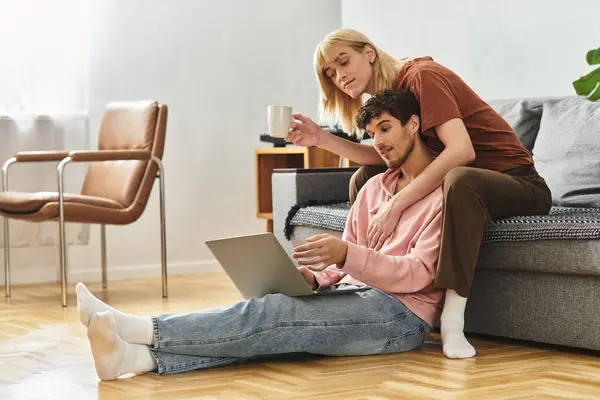 Loving couple relaxes together at home, sharing smiles and warmth while engaging with a laptop. — Stock Photo