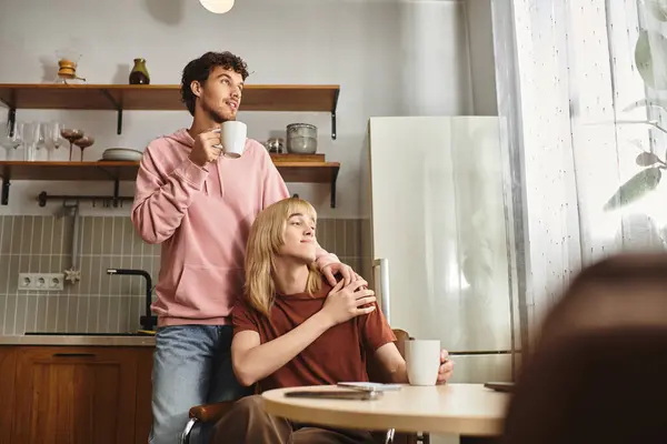 Due uomini condividono un momento tenero sorseggiando caffè in una cucina ben progettata. — Foto stock