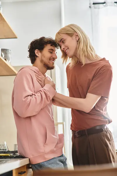 Due uomini condividono un momento di tenerezza in una cucina calda, celebrando amore e connessione. — Foto stock