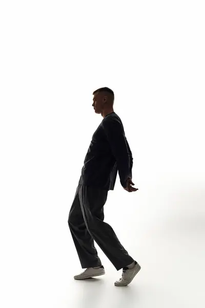 A young man showcases his dynamic dance skills against a minimalist backdrop, embodying elegance. — Stock Photo