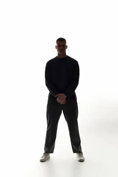 A young man stands firmly with arms crossed, exuding confidence in a sleek, minimalist setting. — Stock Photo