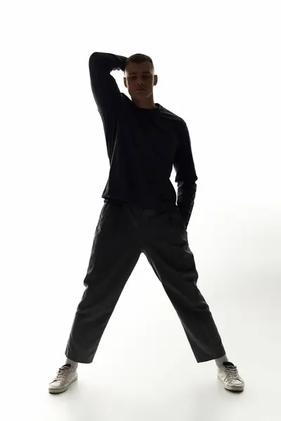 A young man stands tall in a striking pose, highlighted against a bright background. — Stock Photo