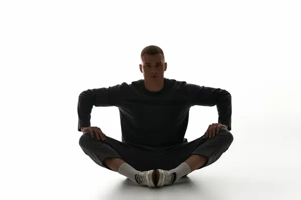 A young man in comfortable clothing is sitting cross legged, exuding calm and focus. — Stock Photo