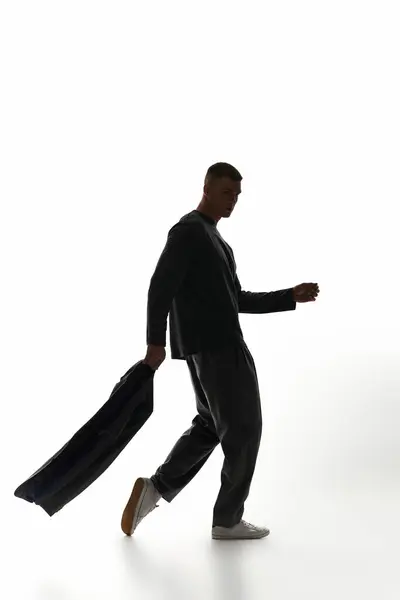 A stylish young man walks effortlessly across a bright studio, exuding confidence and charm. — Stock Photo