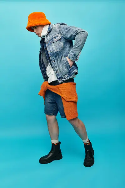 A young man displays a unique blend of colors and styles with confidence in a fashion studio. — Stock Photo