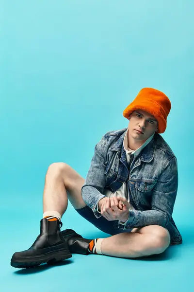 Sitting casually, a young man showcases trendy fashion with vibrant colors and relaxed demeanor. — Stock Photo