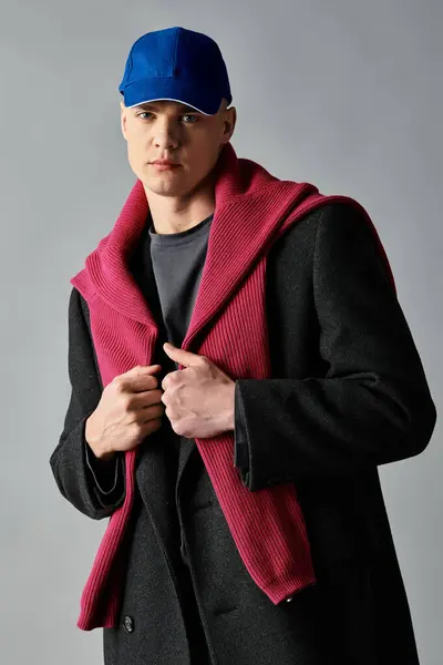A young man stands confidently, wearing a cozy sweater over a sleek coat, expressing modern fashion. — Stock Photo