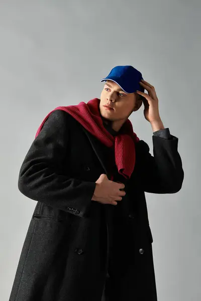 A handsome young man showcases a trendy outfit with a hat and scarf in a stylish indoor setting. — Stock Photo