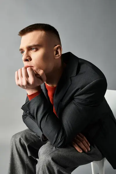 A handsome young man rests his chin on his hand, deep in thought against a sleek backdrop. — Stock Photo