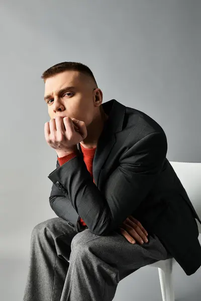 A handsome young man sits pensively, wearing a tailored suit and showcasing modern style. — Stock Photo