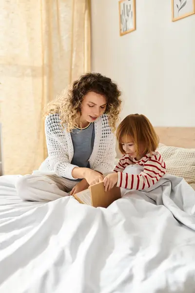 Uma mãe e filha compartilham um momento alegre abrindo um pacote em uma cama macia juntos. — Fotografia de Stock