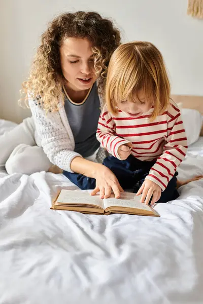 Mère et fille profitent d'un moment joyeux en lisant un livre sur un lit confortable, coller et apprendre. — Photo de stock