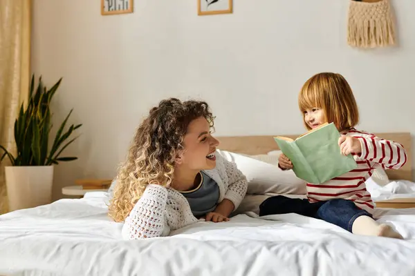 A joyful mother and her daughter share a special moment reading together in their cozy bedroom. — Stock Photo