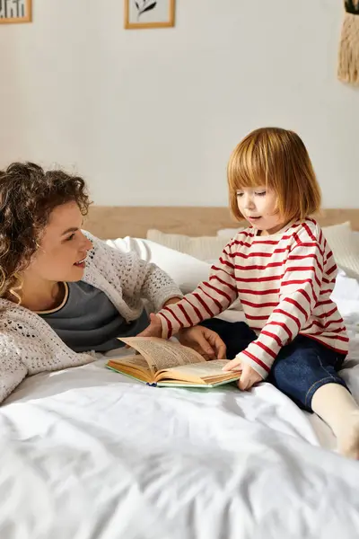 Mother and daughter share a cozy moment reading together on a soft bed, embracing modern parenting. — Stock Photo